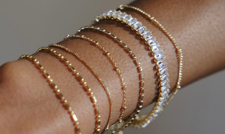 Arm with multiple gold and gemstone bracelets.