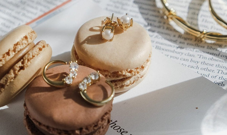 Still life of macarons and jewelry on a paper with text.