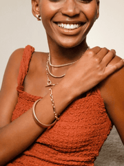 Smiling woman with Chunky Link and Round Hook Toggle jewelry wearing an orange textured top.